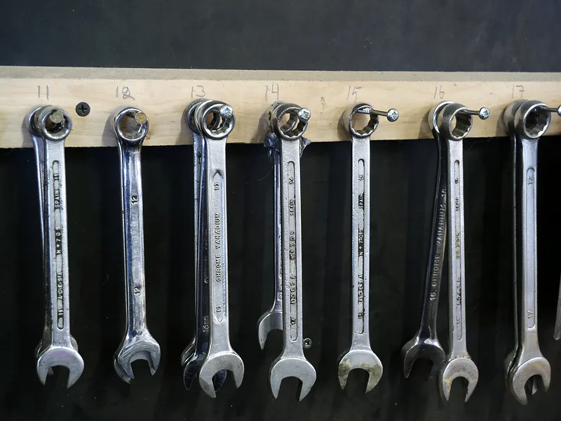 Row of chrome combination wrenches hanging on a tool board